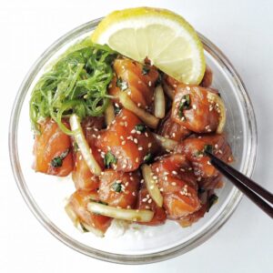 Bowl of Salmon Shoyu poke with chocpsticks.