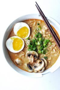 Bowl of instant ramen soup with homemade spicy creamy miso broth with egg, green onions and mushroom for topping.