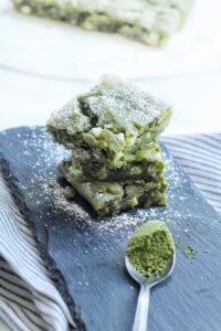 Tower of 3 white chocolate matcha brownies on top of each other.