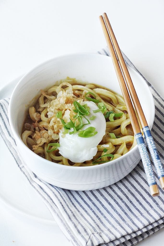 Bowl of Japanese curry udon topped with a poched egg and green onions.