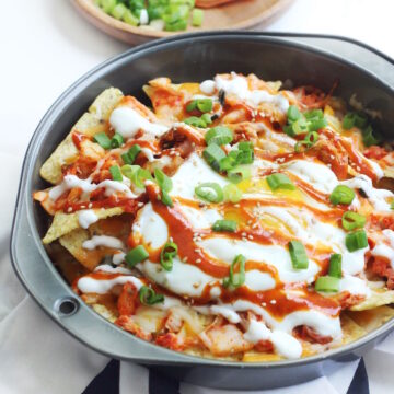 Sideview of a baking dish fill with spicy Korean kimchi nachos.