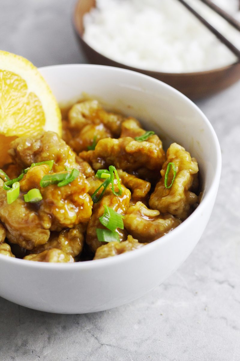 Bowl of Chinese orange chicken with a small bowl of steamed rice on the side.