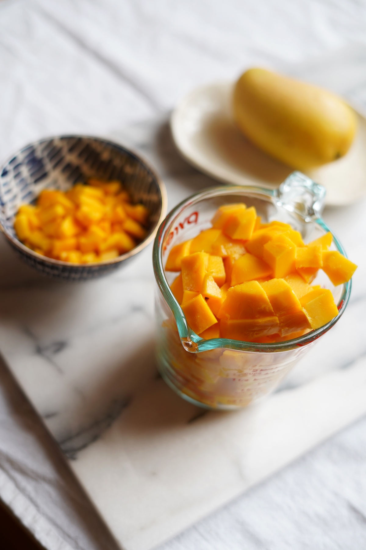 Bowl of cubed mango and another bowl of chopped pieces of mango.