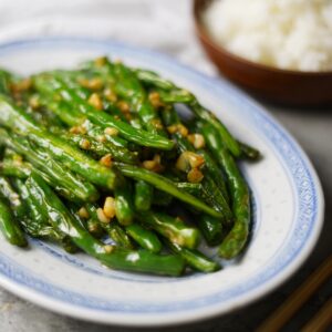 Stir-fried Chinese green beans with garlic on a traditional plate.