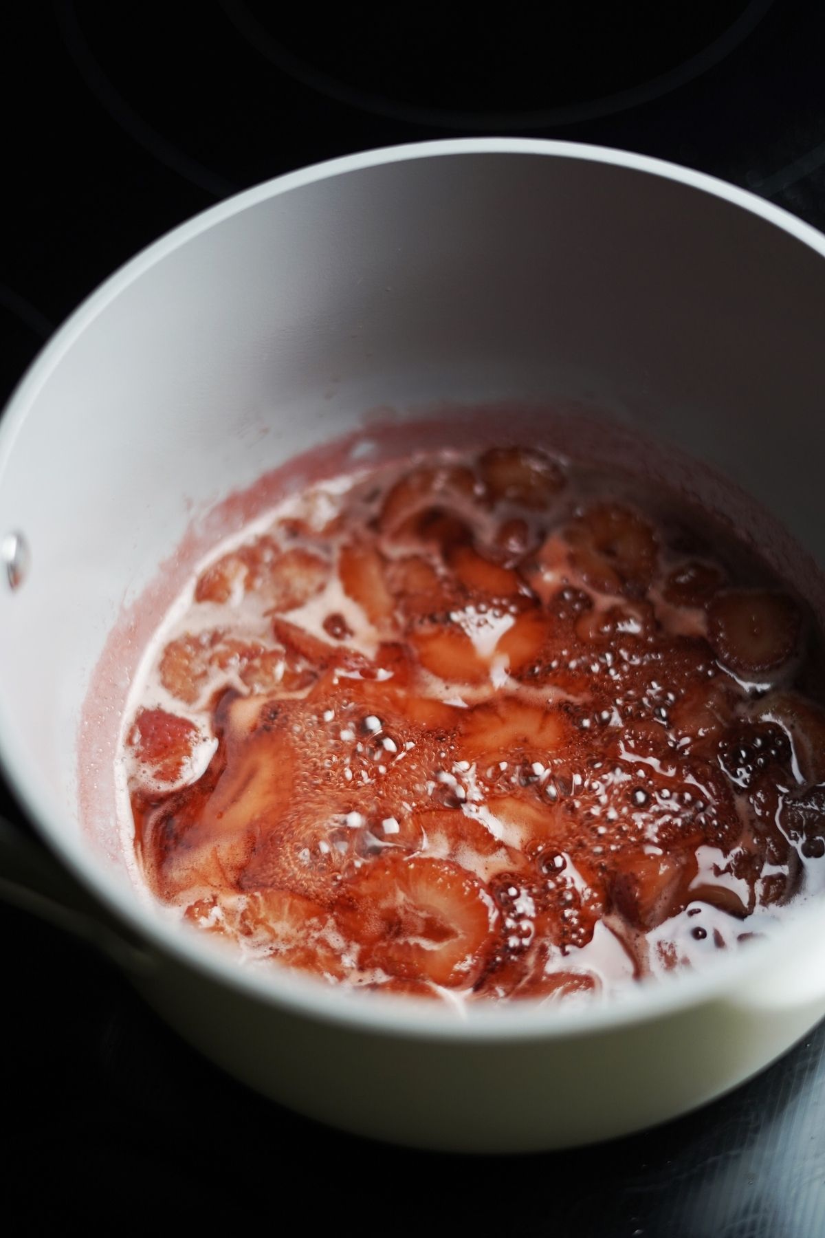 A pot with simmering strawberry syrup