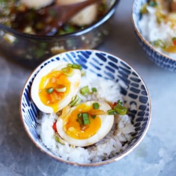 Two halves of Korean marinated egg over a bowl of white rice.