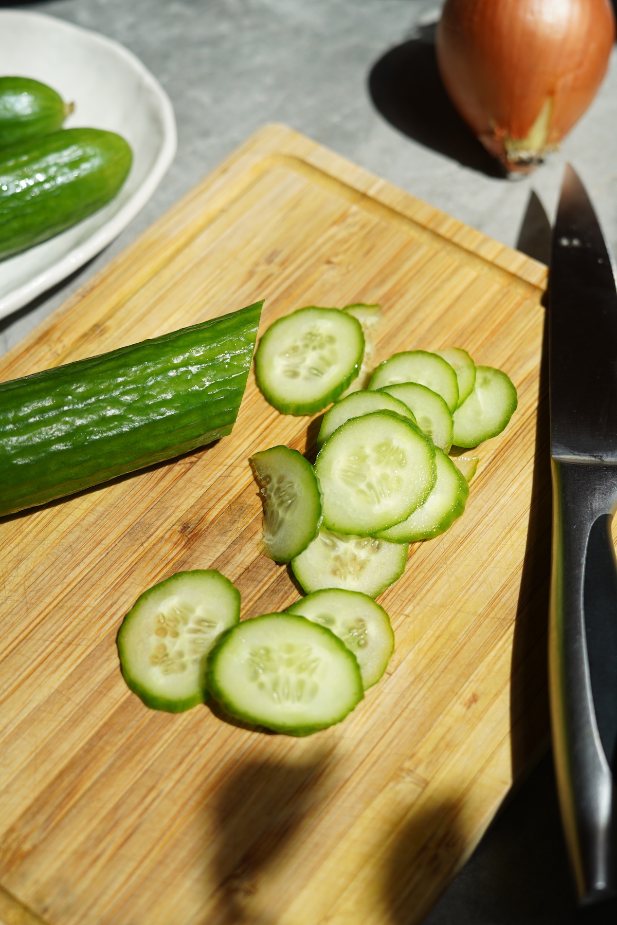 Cucumbers sliced on a cutting board.