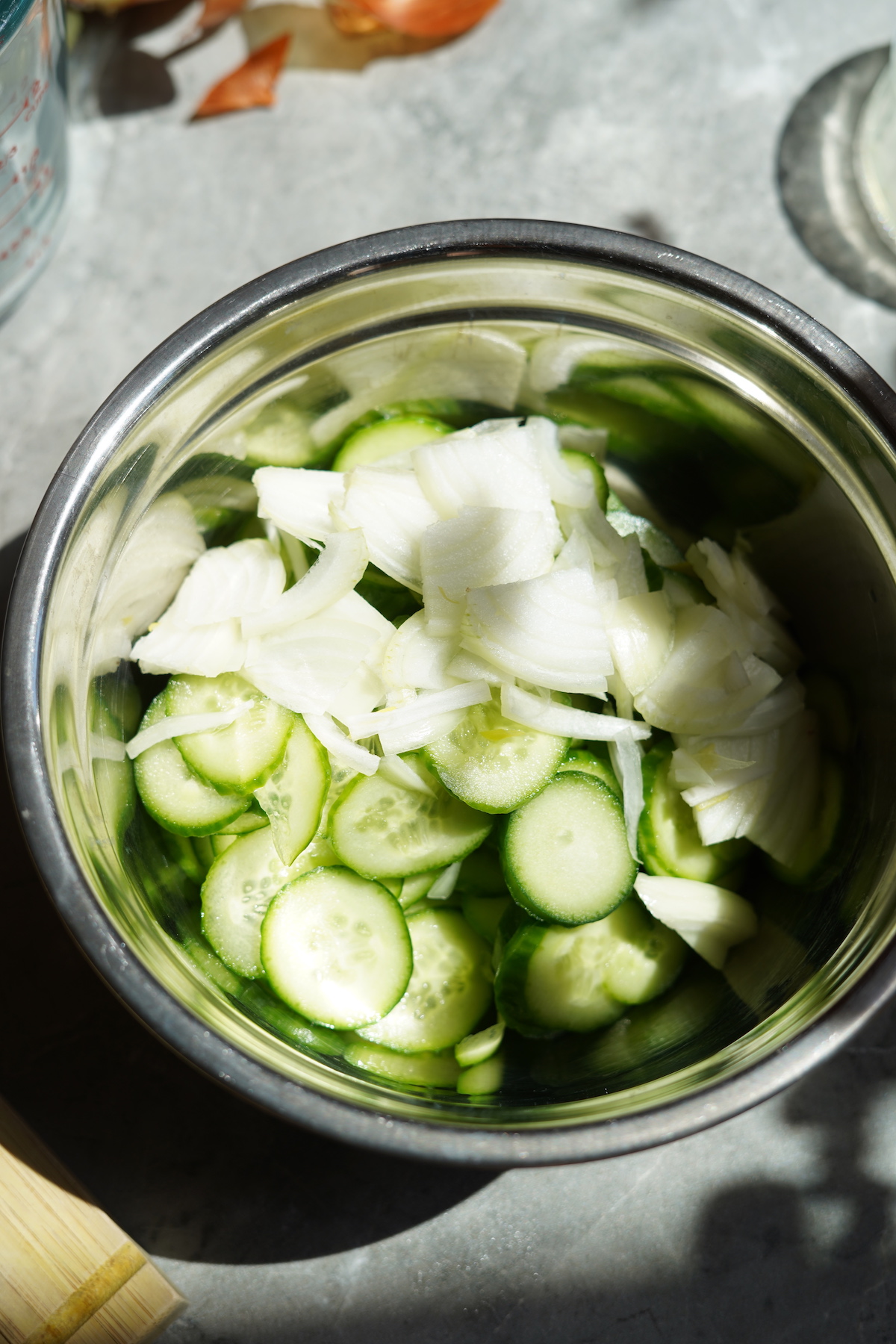 Cucumbers and onions in a mixing bowl.