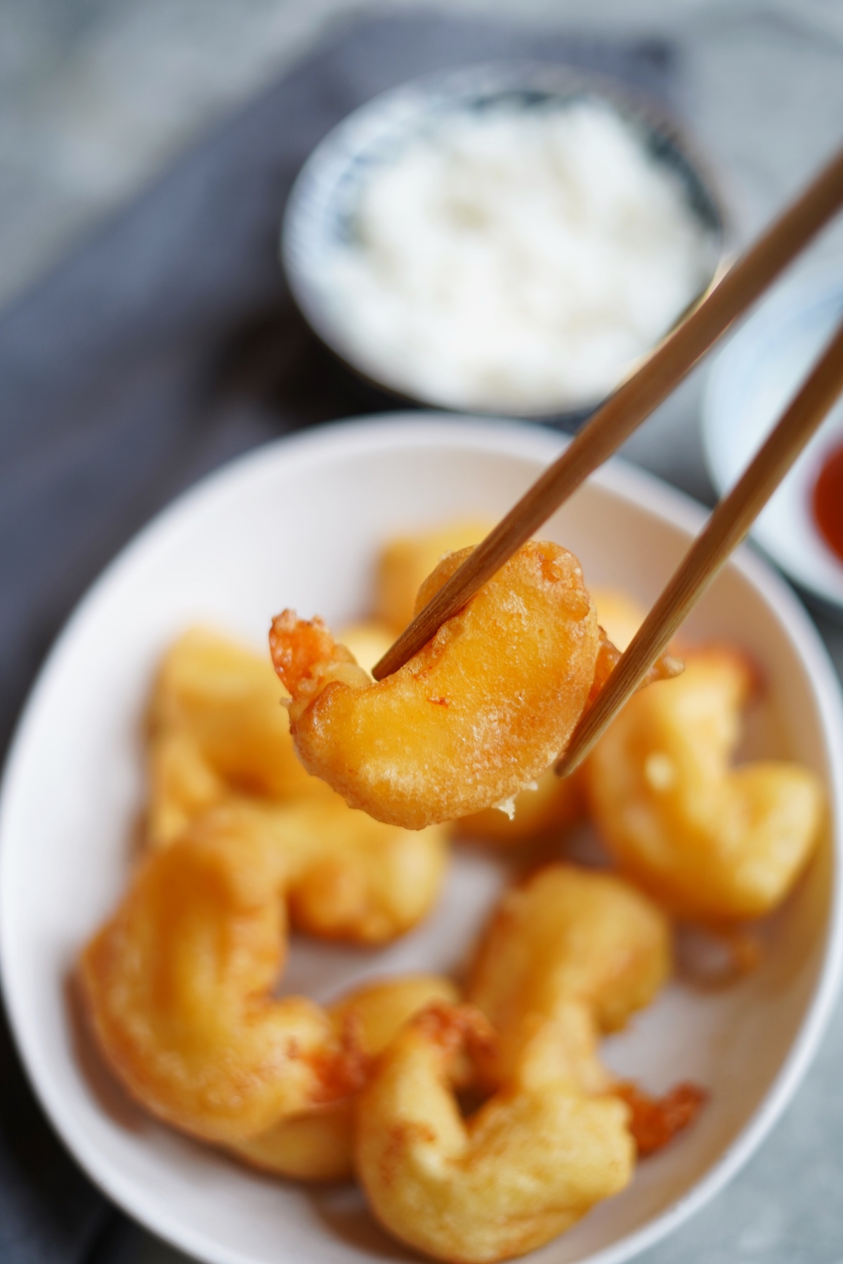 Chopsticks holding a fried shrimp to show the crispy batter.