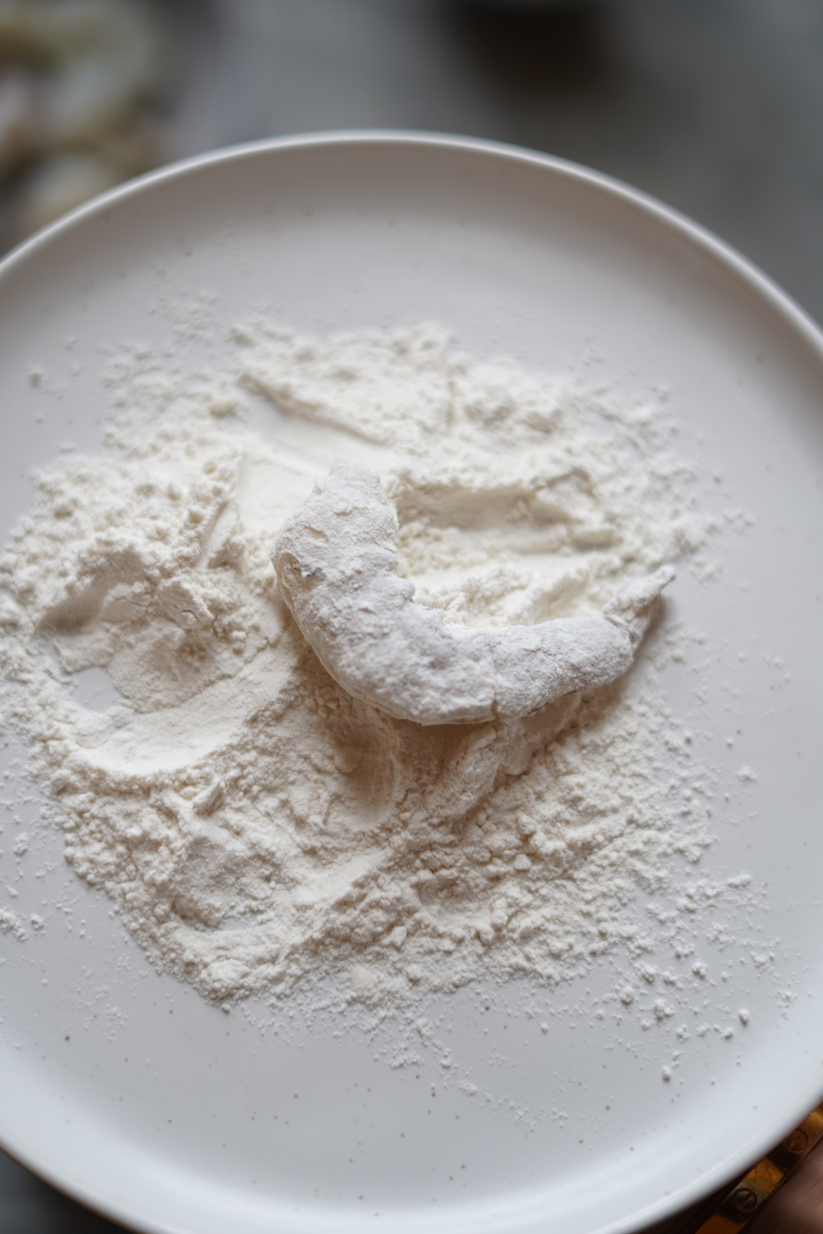 A plate of flour with a coated shrimp.