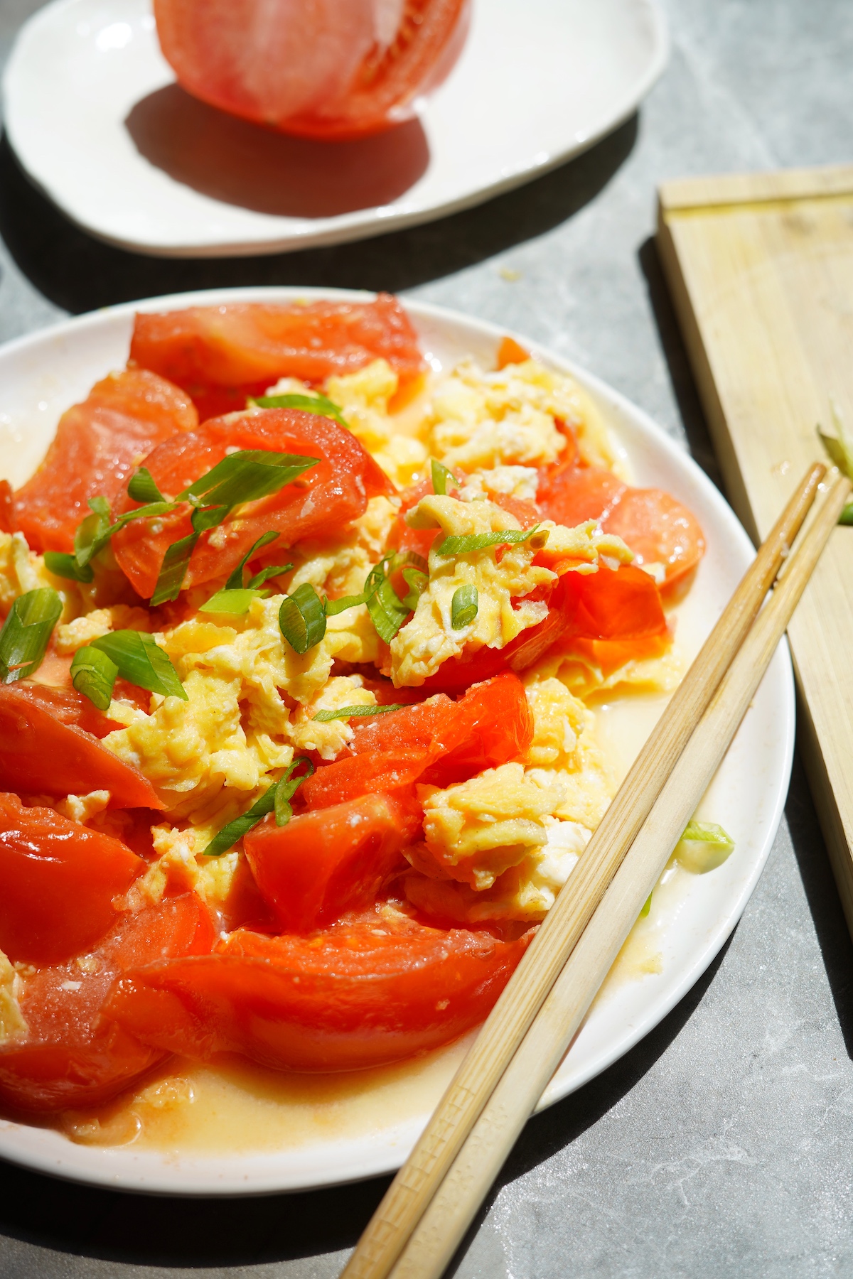 Tomato egg stir-fry on a dish with chopsticks on the side.