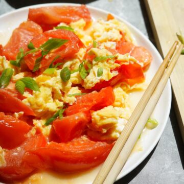 Tomato egg stir-fry on a dish with chopsticks on the side.