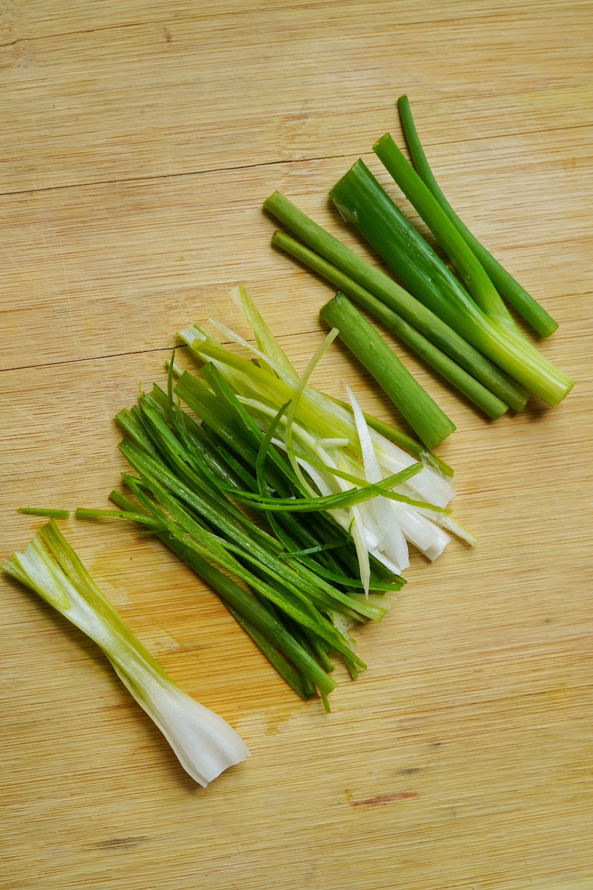 Sliced green onions on a wooden copping board.