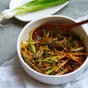 Korean green onion salad in a bowl with a wooden spoon.