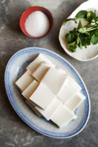 Bird's view of coconut jelly cut into squares stacked on top each other served on a plate.
